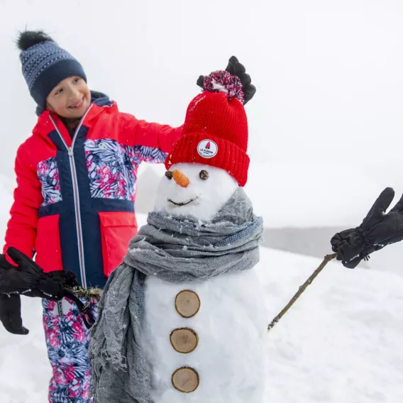 Kind und Schneemann in La Plagne